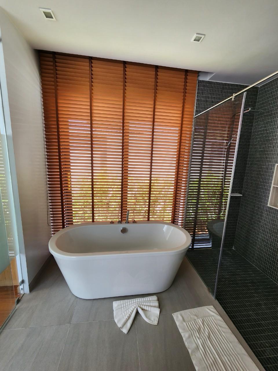 Villa Luma Botanica bathroom with freestanding bathtub, wooden blinds and glass rain shower