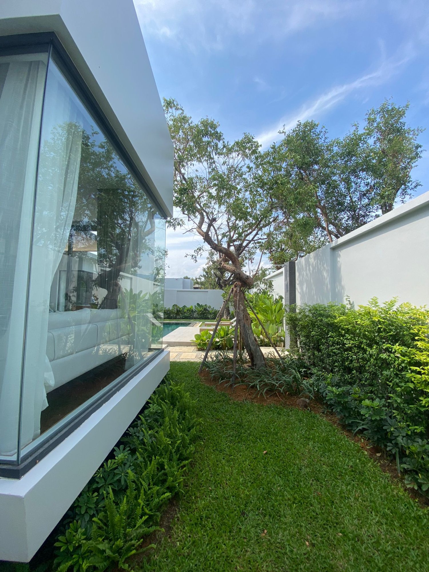Villa Luma Botanica floor-to-ceiling glass facade viewed from lush tropical garden, Phuket