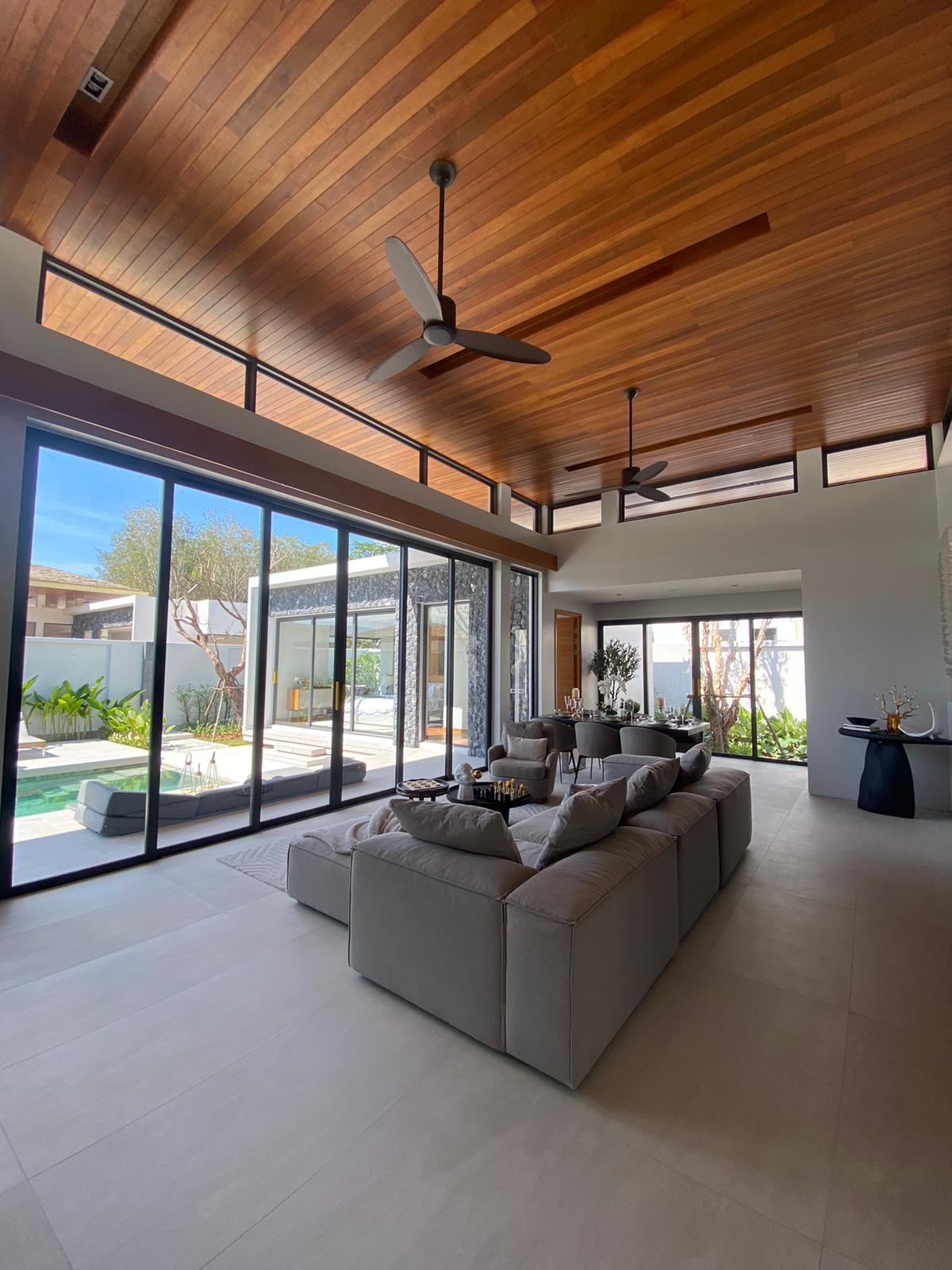 Villa Luma Botanica spacious living room with vaulted timber ceiling, modern sofa and pool courtyard views